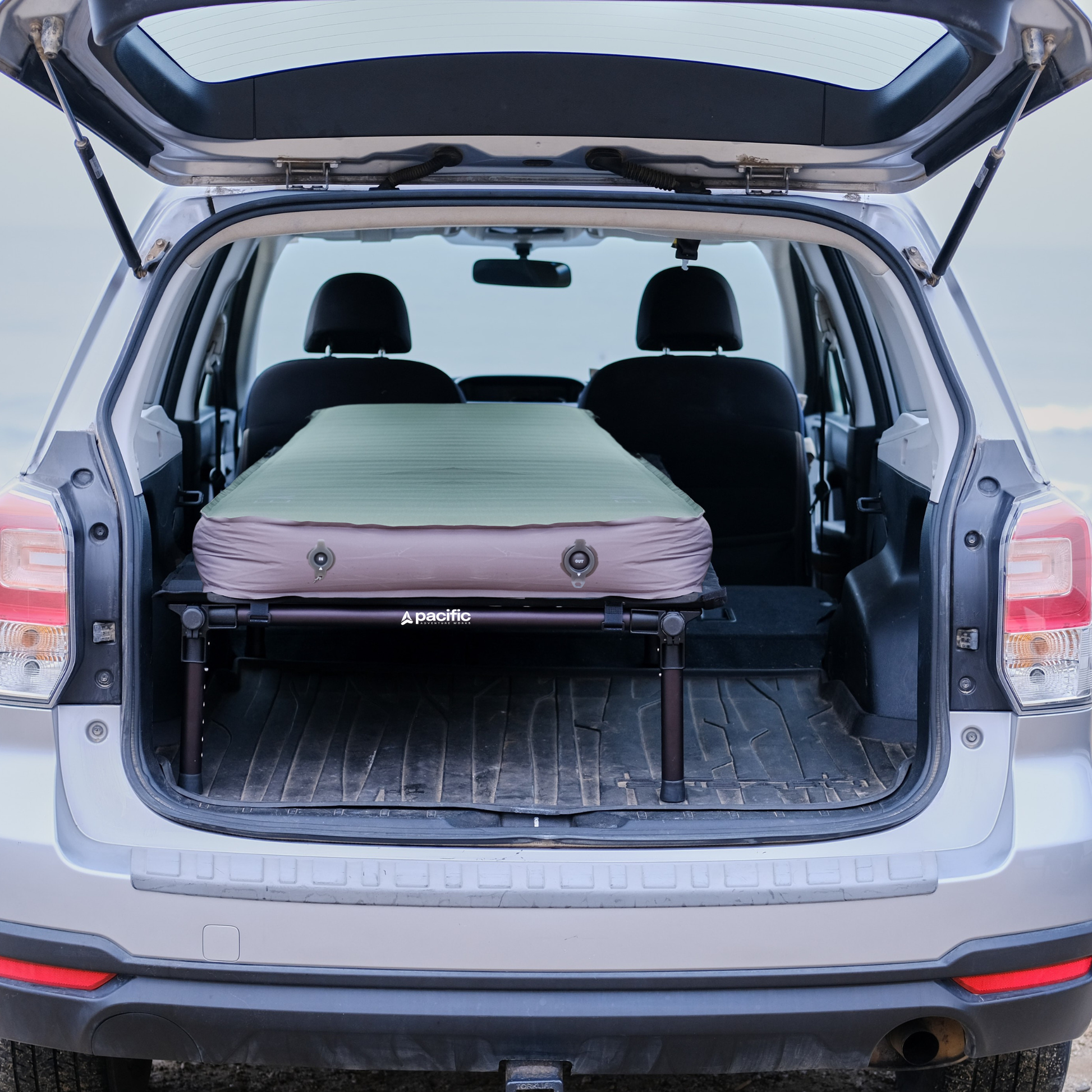 Inflatable camping mattress set up on a hideaway sleeping platform in the back of a car