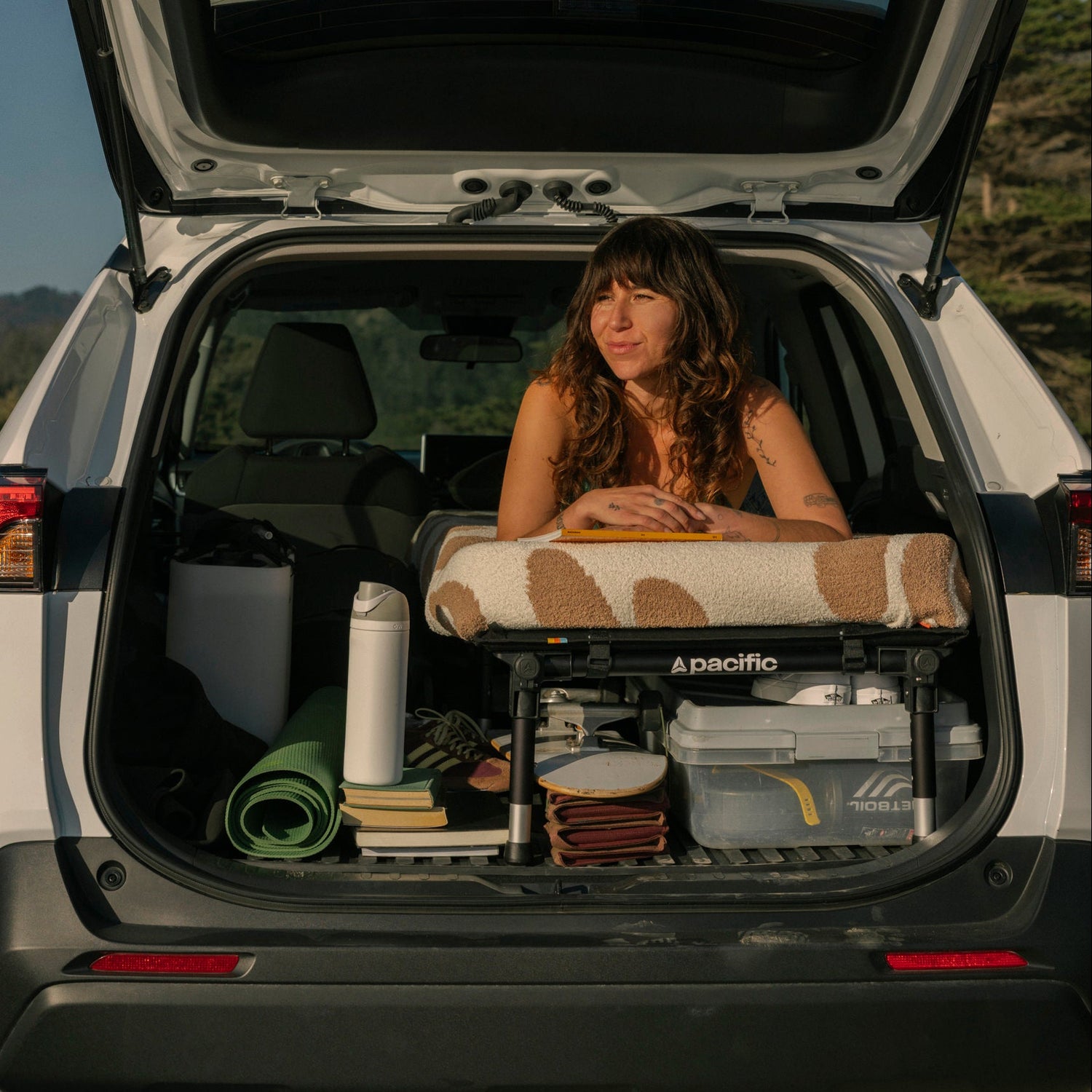 woman laying on hideaway sleeping platform in her rav4 at the beach