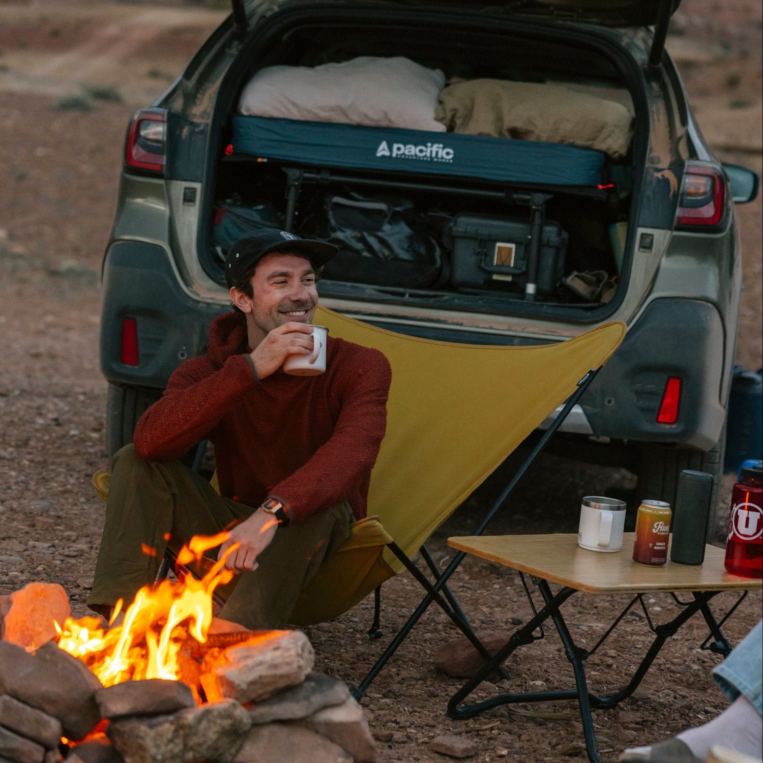 man at campfire sitting in from of his subaru outback with a hideaway platform